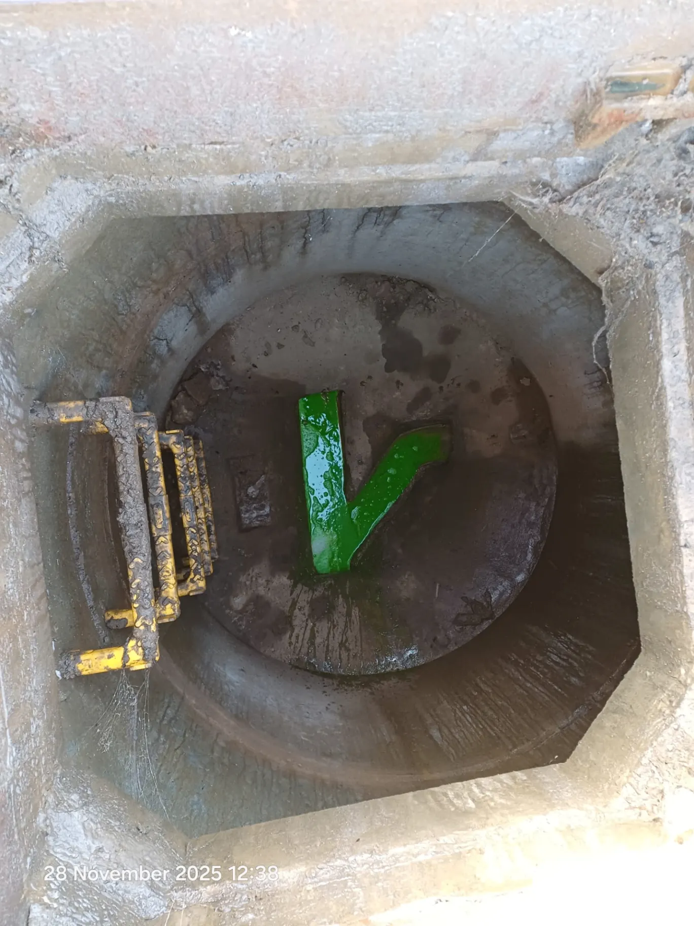 Green tracing dye flowing through a pipe joint in a drainage manhole during a dye test in Northamptonshire
